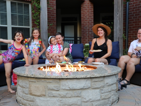 a group of women and children sitting around a fire pit