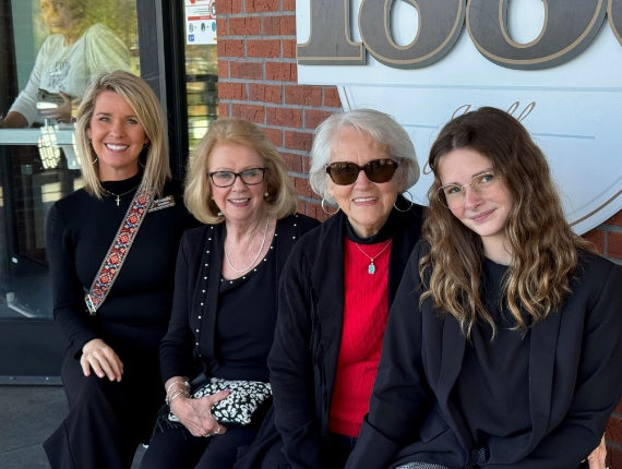 four women sitting outdoors against a brick wall
