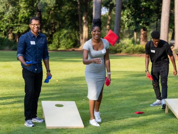 adults playing cornhole outdoors