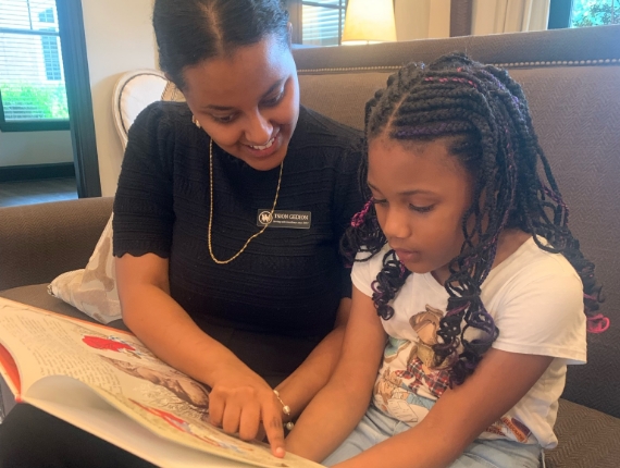 a member of the Walton Communities team reading to a little girl