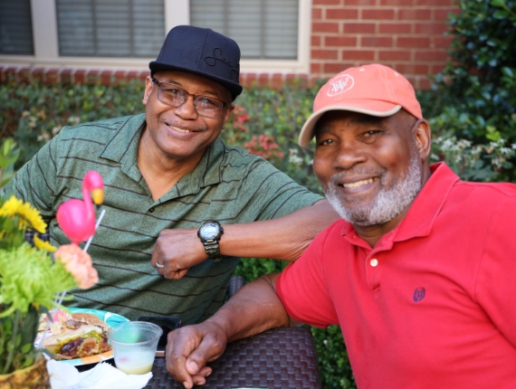 two men sitting and eating outdoors